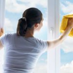 امرأة تغسل النافذة في الطقس المشمس